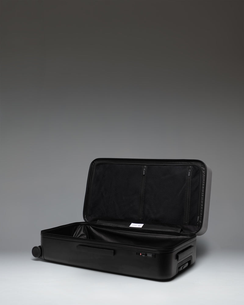 Black Herschel Heritage Hardshell Large Luggage on a white background, showing a side view profile.