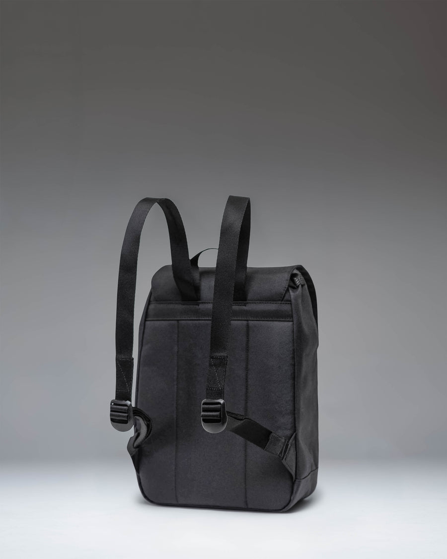 Herschel Retreat Mini Backpack in solid black, featuring dual rubber straps with magnetic pin clips and a woven classic brand label.