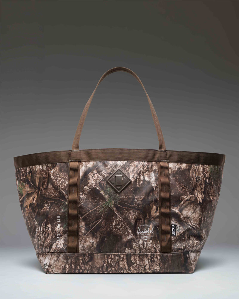Herschel Supply Co. Realtree All Season Gear Tote 63 L in Realtree APX Camo pattern, showing a spacious design perfect for outdoor gear.