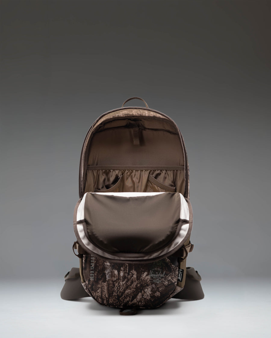 Herschel Supply Co. Realtree All Season Backpack 29 L in Realtree APX Camo pattern showing side pockets and straps.