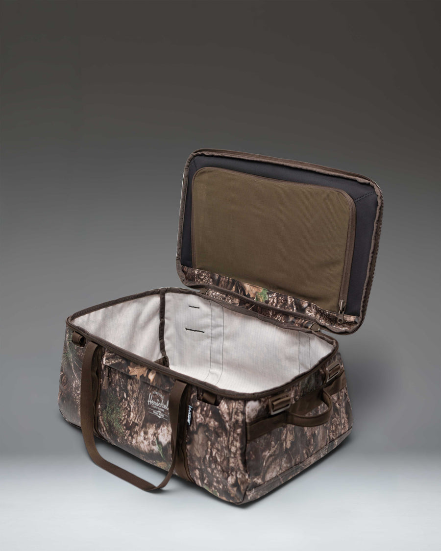 Herschel Supply Co. Realtree All Season Duffle 41 L bag in Realtree APX Camo pattern shown from a side view perspective.