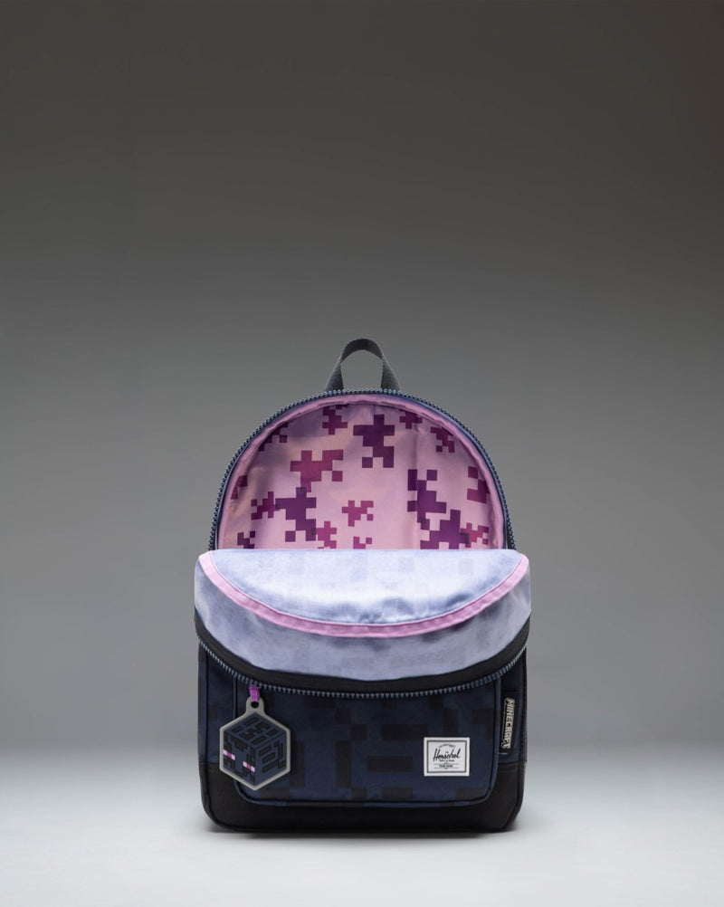 Minecraft Herschel Heritage Kids Backpack in Enderman black with pixelated purple details and a square logo patch on the front pocket.