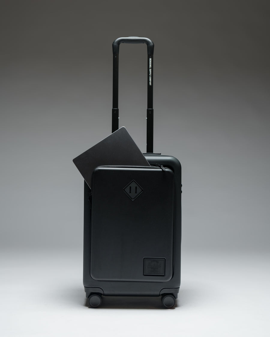 Herschel Heritage Hardshell Pro Large Carry On luggage in Black, shown from the front with a textured hard shell and retractable handle.