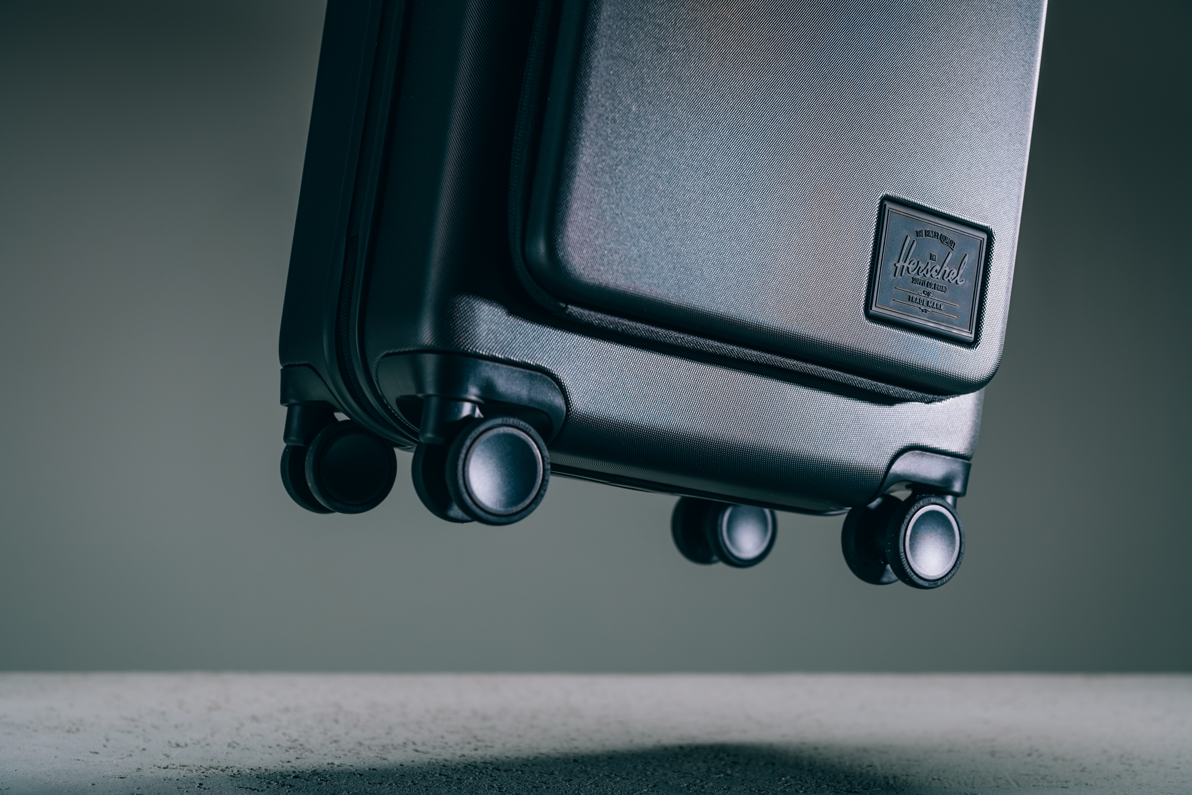 Herschel Heritage Hardshell Pro Large Carry On suitcase in black, showcasing its durable hardshell exterior, wheels, and front pocket features.