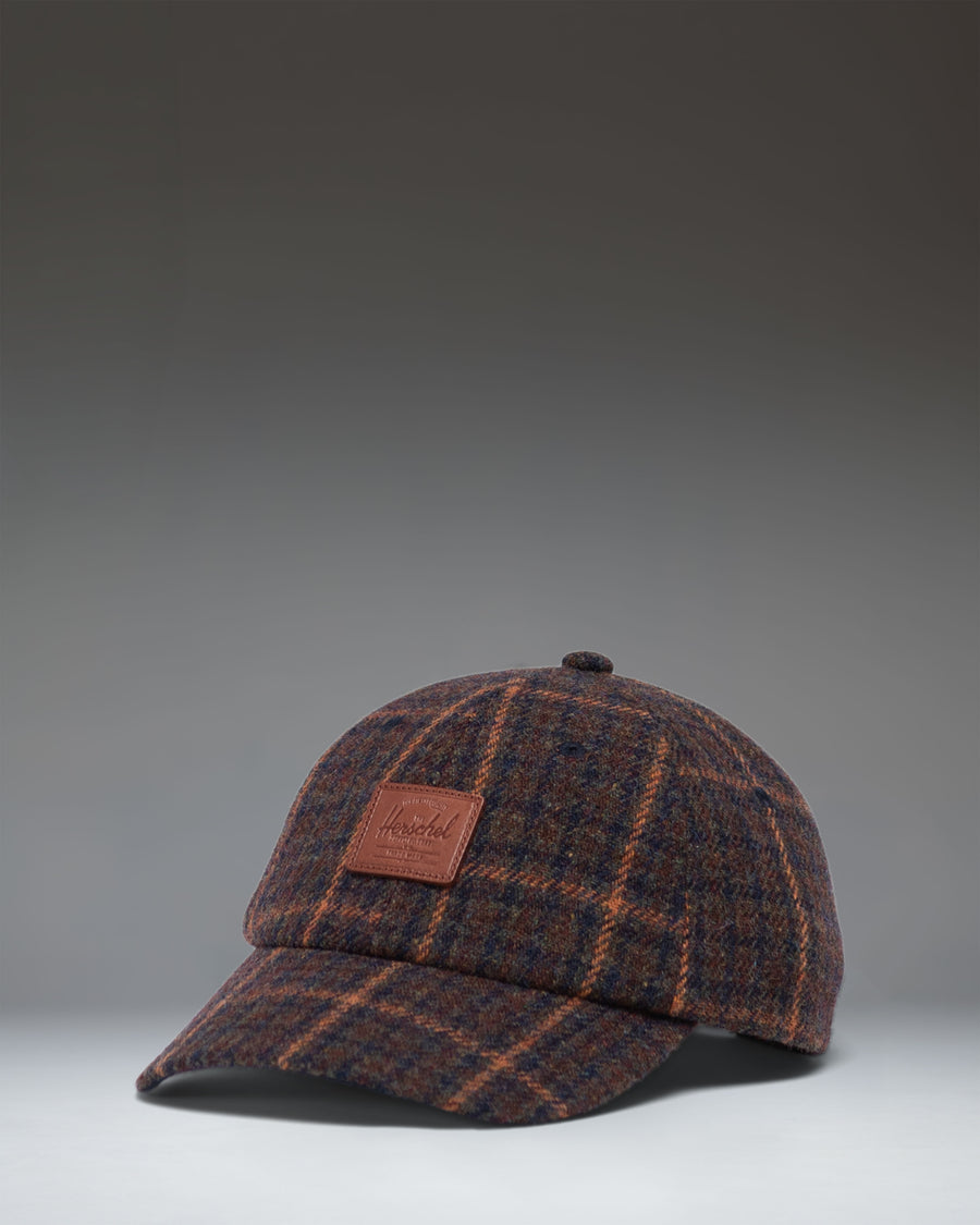 Herschel Supply Co. dark plaid backpack with tan brown straps and details, shown against a clean white background.