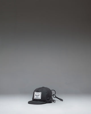 Herschel Supply Co. Sylas Classic Cap Bag Charm in black, showing the front view of a miniature baseball cap keychain accessory.