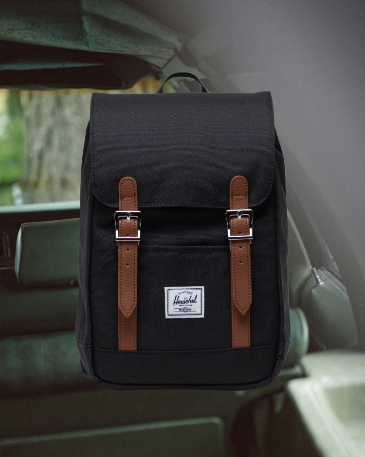 Herschel Retreat Mini Backpack in black, showing the front view with its signature rubber strap closures on a mobile-optimized clean background.